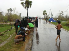 雨の中幹線道路に出て支援の車を待つ人々。村そのものが消滅し、住む場所を完全に失った人も多い。