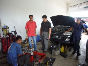 ロスラン・ジャック氏（左から2人目）の自動車整備工場を訪問し、作業の様子を視察する永石事務局長
