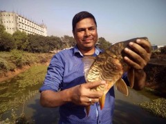 バングラデシュセンターの池で育てた魚を手にするマイヌルさん